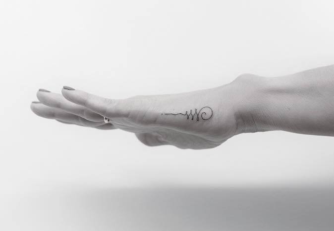 Unalome tattoo on side of palm.