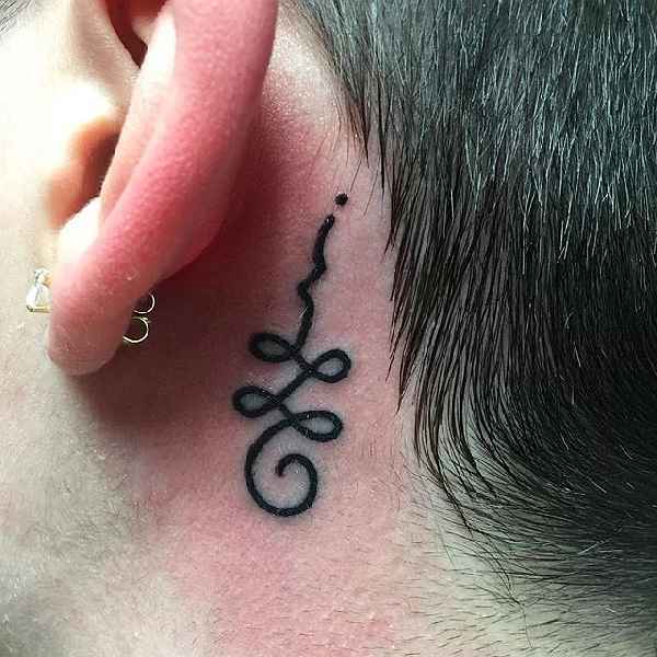 Unalome tattoo behind the ear.