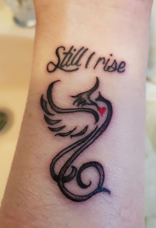 Phoenix Tattoo and 'Still I Rise' written on wrist.